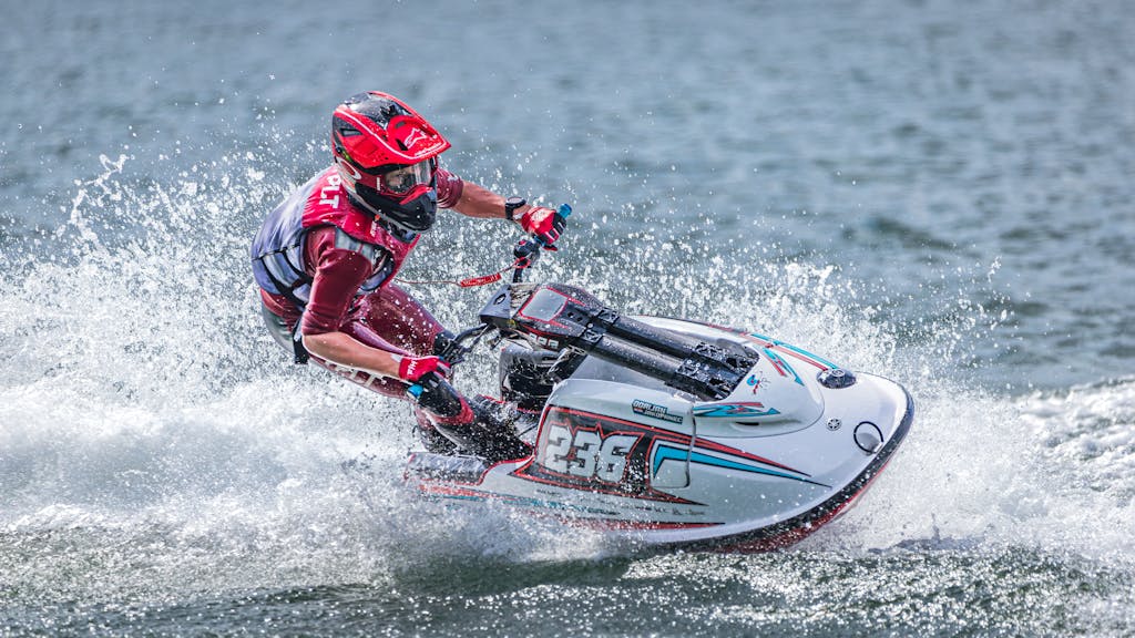 Dynamic shot of an athlete racing a jet ski, splashing water in a thrilling speed sport.